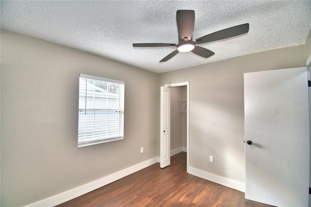 7504 Willow Wisp Dr E, Lakeland, FL 33810 - unfurnished bedroom featuring baseboards, a textured ceiling, dark wood finished floors, a walk in closet, and a ceiling fan