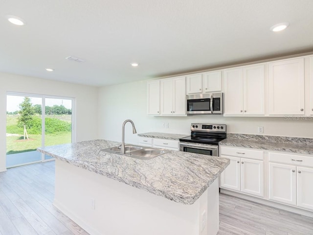 3124 N Chamberlain Blvd, North Port, FL 34286 - kitchen featuring appliances with stainless steel finishes, a sink, white cabinets, light wood-style floors, and light stone counters