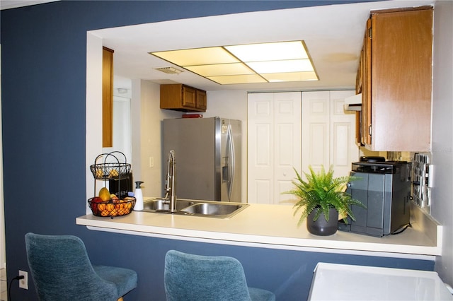 4364 White Pine Ave Unit 3, Orlando, FL 32811 - kitchen featuring stainless steel fridge with ice dispenser, brown cabinets, a sink, a peninsula, and a kitchen breakfast bar