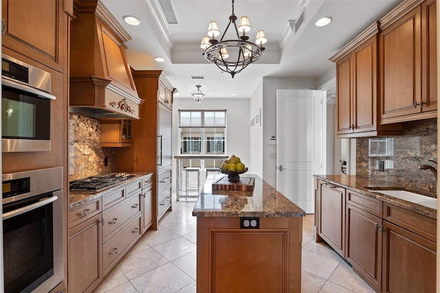140 E Morse Blvd Unit J, Winter Park, FL 32789 - kitchen featuring a kitchen island, stainless steel gas stovetop, a chandelier, a tray ceiling, and brown cabinetry