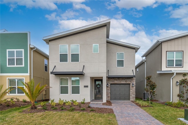 3004 Protagonist St, Kissimmee, FL 34746 - modern home featuring stucco siding, an attached garage, decorative driveway, a front yard, and stone siding