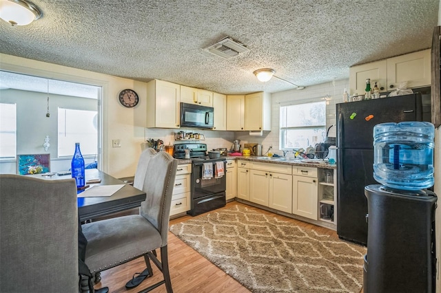 1711 E Sewaha St, Tampa, FL 33612 - kitchen featuring black appliances, light wood-style floors, and a textured ceiling