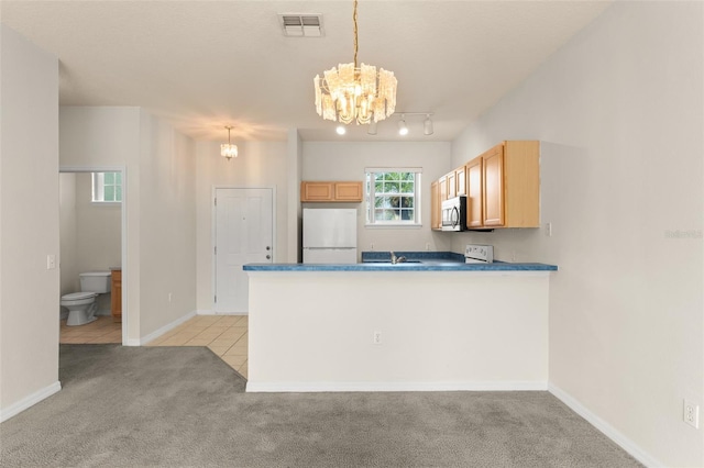 214 Monroe Cir, Davenport, FL 33896 - kitchen featuring freestanding refrigerator, stainless steel microwave, a chandelier, light carpet, and a peninsula