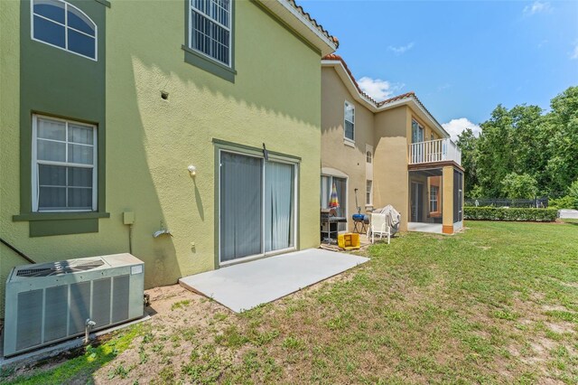 214 Monroe Cir, Davenport, FL 33896 - rear view of property featuring cooling unit, stucco siding, a patio, a lawn, and a balcony