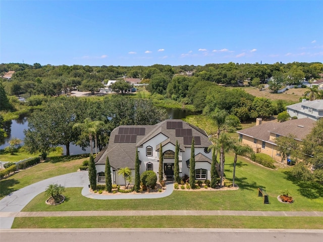8131 Vineland Oaks Blvd, Orlando, FL 32835 - view of front of home featuring roof mounted solar panels, a front yard, a water view, stucco siding, and roof with shingles