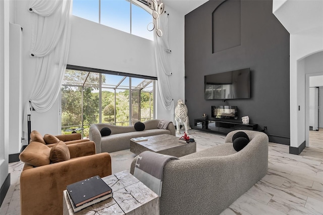 8131 Vineland Oaks Blvd, Orlando, FL 32835 - living room featuring a high ceiling, light marble finish floors, plenty of natural light, arched walkways, and baseboards