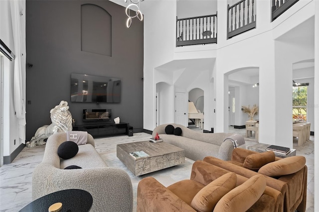 8131 Vineland Oaks Blvd, Orlando, FL 32835 - living room with arched walkways, marble look tiles, a towering ceiling, and baseboards