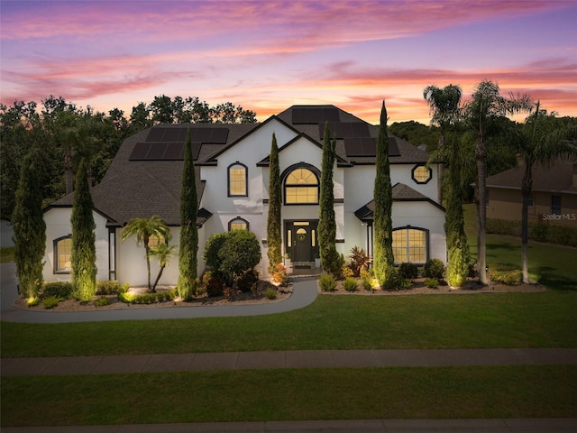 8131 Vineland Oaks Blvd, Orlando, FL 32835 - french provincial home with stucco siding, a front yard, roof mounted solar panels, and a shingled roof
