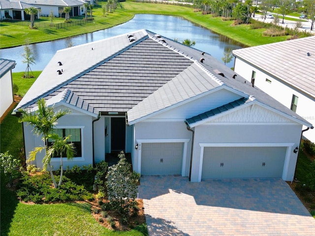 410 SE Vallarta Dr, Port St Lucie, FL 34984 - view of front facade with a water view, a garage, decorative driveway, stucco siding, and a tiled roof