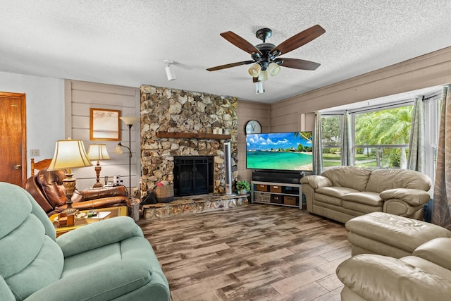 310 E Gulley Ave, Oakland, FL 34760 - living room with wood finished floors, a textured ceiling, a ceiling fan, and a stone fireplace