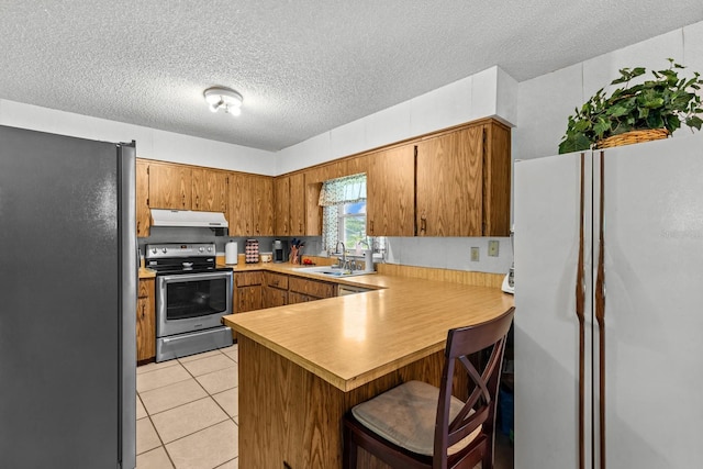 310 E Gulley Ave, Oakland, FL 34760 - kitchen with stainless steel appliances, under cabinet range hood, a peninsula, brown cabinetry, and light countertops