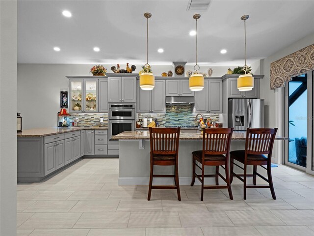 8818 Bismarck Palm Dr, Winter Garden, FL 34787 - kitchen featuring gray cabinets, appliances with stainless steel finishes, tasteful backsplash, an island with sink, and recessed lighting