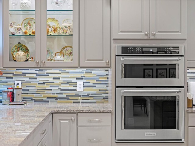 8818 Bismarck Palm Dr, Winter Garden, FL 34787 - kitchen featuring double oven, backsplash, white cabinetry, and light stone countertops