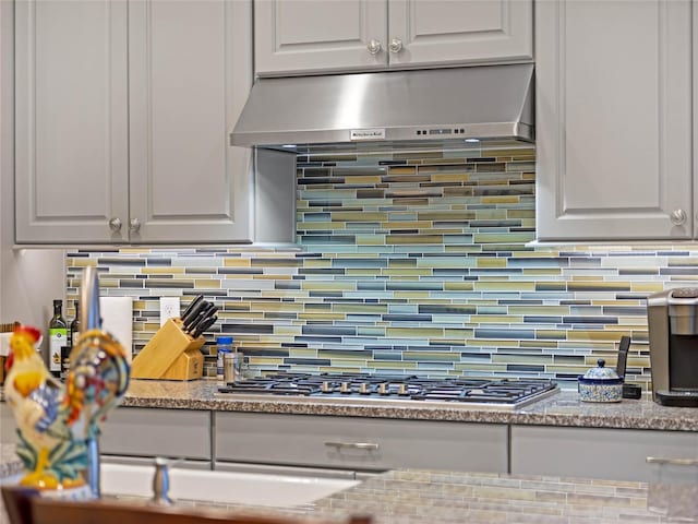 8818 Bismarck Palm Dr, Winter Garden, FL 34787 - kitchen view of ventilation hood, decorative backsplash, white cabinetry, and stainless steel gas stovetop