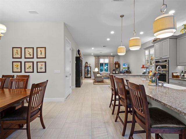 8818 Bismarck Palm Dr, Winter Garden, FL 34787 - kitchen featuring gray cabinets, a kitchen breakfast bar, stainless steel double oven, stone countertops, and recessed lighting