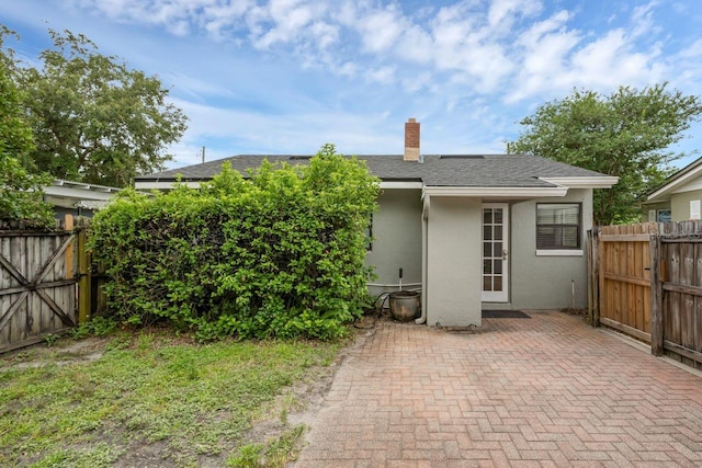 1021 N Forest Ave, Orlando, FL 32803 - back of property featuring stucco siding, a patio, a chimney, and a shingled roof