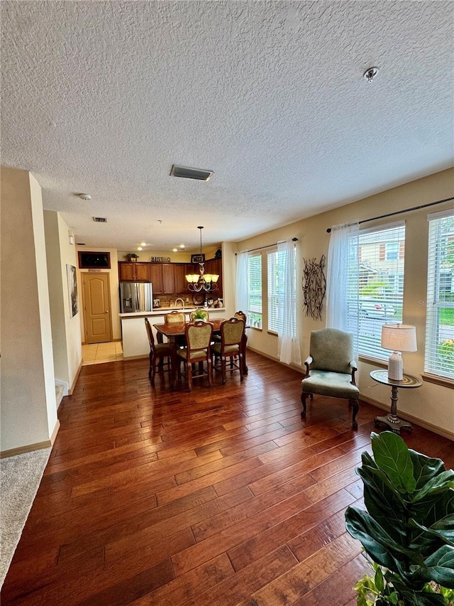 10350 Lake District Ln Unit S, Orlando, FL 32832 - dining space with a textured ceiling, dark wood-style flooring, a chandelier, and baseboards