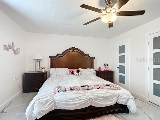 516 Petes Ln, Davenport, FL 33837 - bedroom with baseboards, light marble finish flooring, and ceiling fan