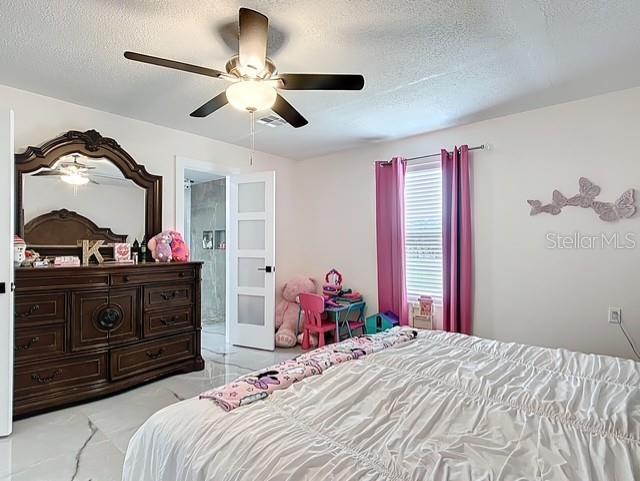 516 Petes Ln, Davenport, FL 33837 - bedroom featuring a textured ceiling, light marble finish floors, and ceiling fan