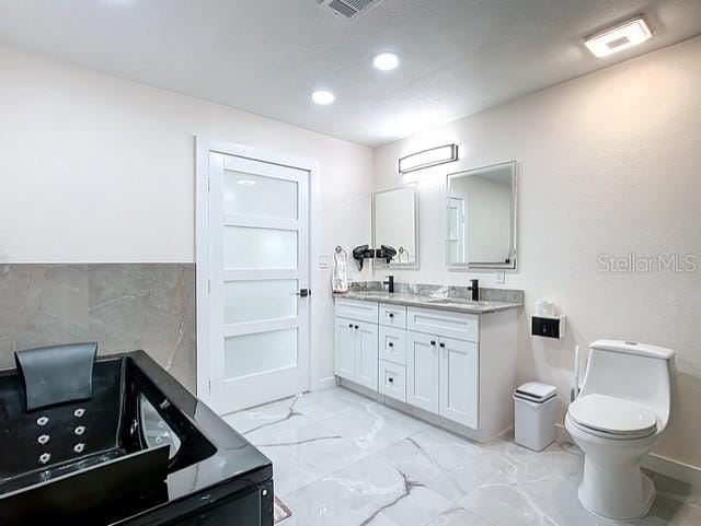 516 Petes Ln, Davenport, FL 33837 - full bathroom with double vanity, a tub with jets, toilet, marble look tile flooring, and recessed lighting