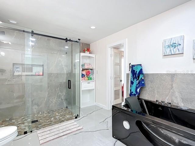 516 Petes Ln, Davenport, FL 33837 - bathroom featuring toilet, marble tiled flooring, a marble finish shower, baseboards, and recessed lighting