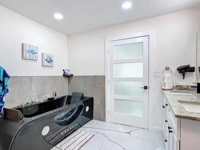 516 Petes Ln, Davenport, FL 33837 - laundry area featuring cabinet space, recessed lighting, and tile walls