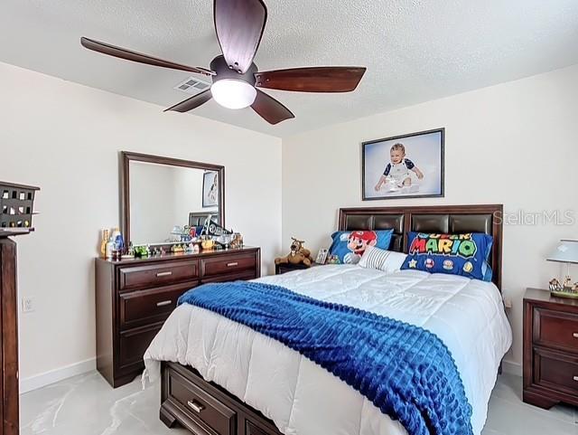 516 Petes Ln, Davenport, FL 33837 - bedroom with ceiling fan, a textured ceiling, and baseboards