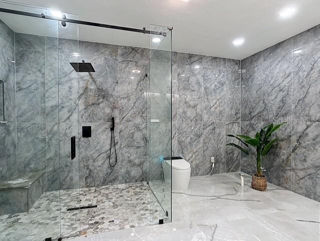 516 Petes Ln, Davenport, FL 33837 - full bathroom featuring a marble finish shower, toilet, and tile walls