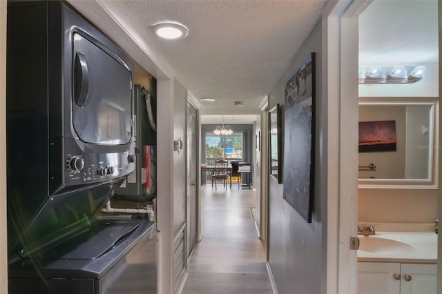1051 S Highland St Unit 5E, Mount Dora, FL 32757 - hallway with estacked washer and dryer, a textured ceiling, a sink, light wood finished floors, and a chandelier