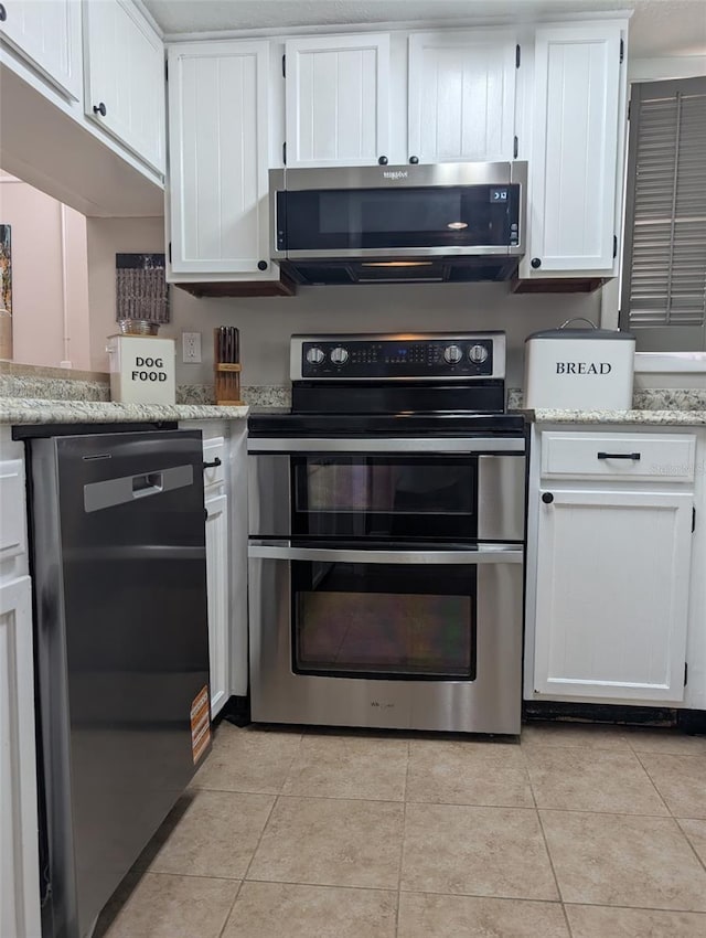 1051 S Highland St Unit 5E, Mount Dora, FL 32757 - kitchen featuring stainless steel appliances, white cabinets, light tile patterned floors, and light stone counters