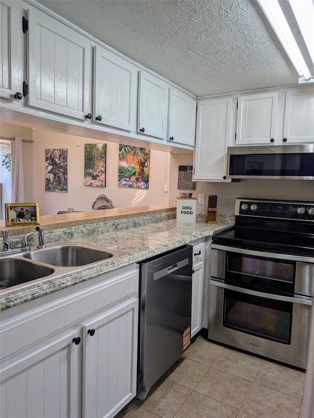 1051 S Highland St Unit 5E, Mount Dora, FL 32757 - kitchen featuring stainless steel appliances, white cabinets, light tile patterned floors, and a textured ceiling
