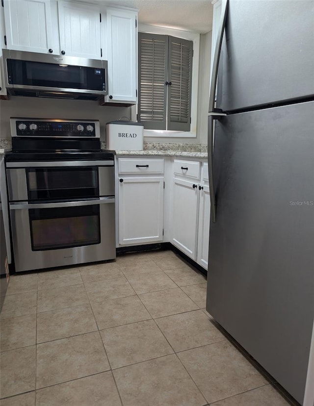1051 S Highland St Unit 5E, Mount Dora, FL 32757 - kitchen with stainless steel appliances, white cabinetry, and light tile patterned floors