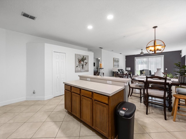 204 Cotswold Cir, Davenport, FL 33837 - kitchen featuring a chandelier, light countertops, light tile patterned flooring, brown cabinetry, and a kitchen island