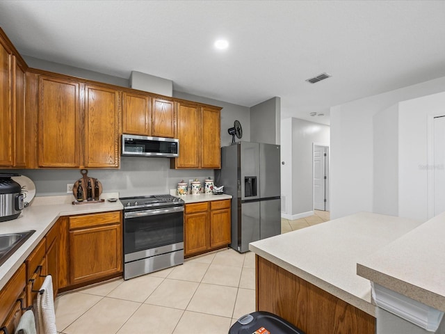 204 Cotswold Cir, Davenport, FL 33837 - kitchen with stainless steel appliances, brown cabinets, light tile patterned floors, light countertops, and recessed lighting