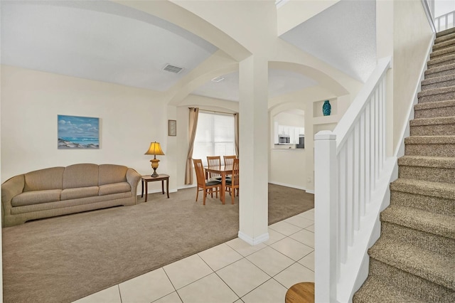 8622 La Isla Dr, Kissimmee, FL 34747 - foyer entrance with light colored carpet, arched walkways, light tile patterned floors, stairway, and baseboards