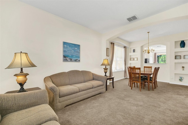 8622 La Isla Dr, Kissimmee, FL 34747 - carpeted living room with arched walkways, a chandelier, built in shelves, and baseboards