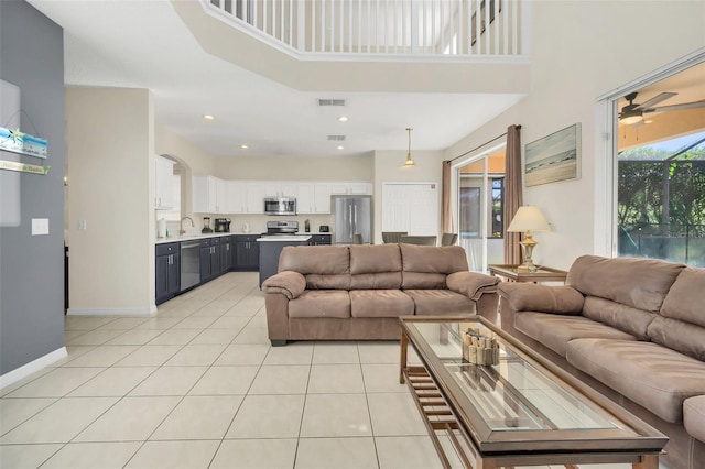 8622 La Isla Dr, Kissimmee, FL 34747 - living room featuring light tile patterned flooring, a towering ceiling, ceiling fan, and baseboards