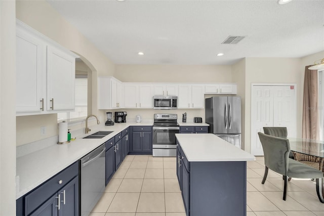 8622 La Isla Dr, Kissimmee, FL 34747 - kitchen featuring appliances with stainless steel finishes, a sink, white cabinets, a kitchen island, and light countertops
