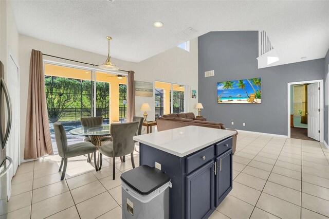 8622 La Isla Dr, Kissimmee, FL 34747 - kitchen featuring light tile patterned floors, ceiling fan, light countertops, a kitchen island, and high vaulted ceiling