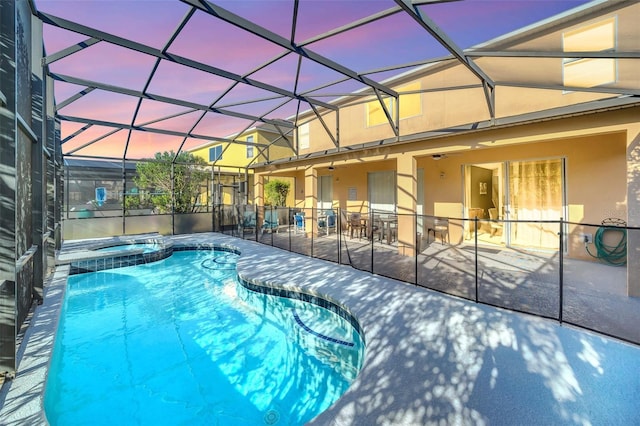 8622 La Isla Dr, Kissimmee, FL 34747 - pool at dusk with a patio area, a pool with connected hot tub, a ceiling fan, and a lanai