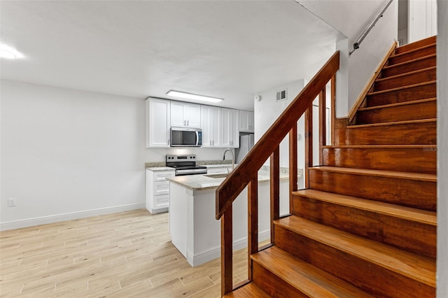 131 Stefanik Rd, Winter Park, FL 32792 - kitchen with appliances with stainless steel finishes, baseboards, a sink, light wood-style floors, and light stone counters