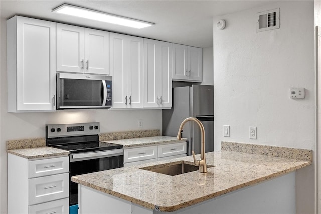 131 Stefanik Rd, Winter Park, FL 32792 - kitchen with stainless steel appliances, a sink, white cabinetry, a peninsula, and light stone counters