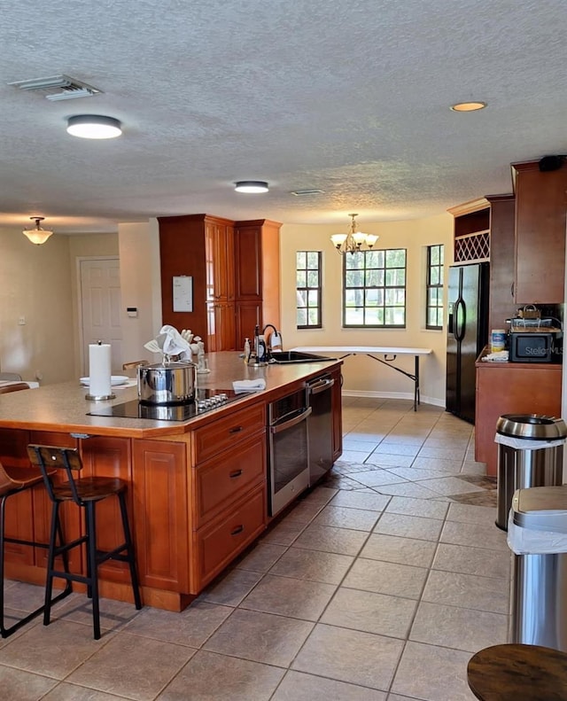 10012 Lake Louisa Rd, Clermont, FL 34711 - kitchen featuring black appliances, a sink, an island with sink, a chandelier, and a textured ceiling