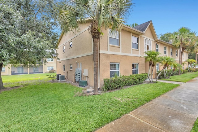 9900 Sweepstakes Ln Unit 1, Orlando, FL 32837 - view of side of home with stucco siding, a yard, central AC unit, and a residential view