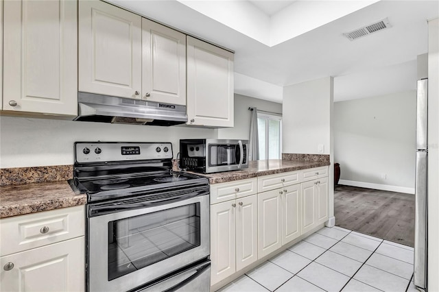 9900 Sweepstakes Ln Unit 1, Orlando, FL 32837 - kitchen featuring under cabinet range hood, appliances with stainless steel finishes, white cabinetry, light tile patterned flooring, and baseboards