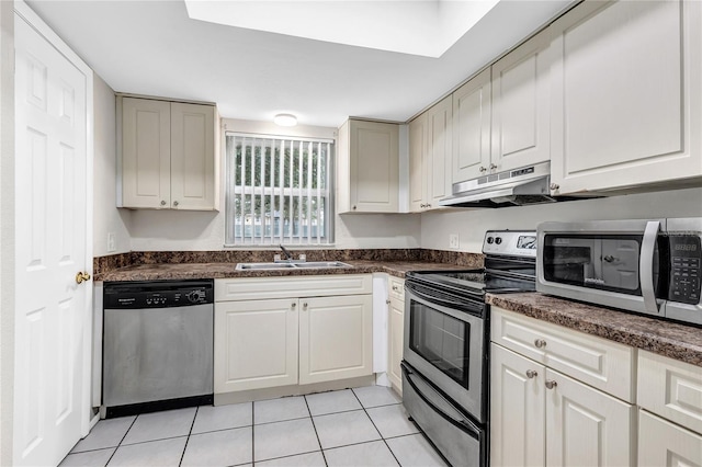 9900 Sweepstakes Ln Unit 1, Orlando, FL 32837 - kitchen featuring appliances with stainless steel finishes, under cabinet range hood, a sink, dark countertops, and light tile patterned floors