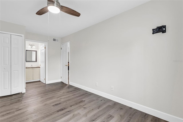 9900 Sweepstakes Ln Unit 1, Orlando, FL 32837 - unfurnished bedroom featuring baseboards, wood finished floors, a closet, ensuite bathroom, and a sink