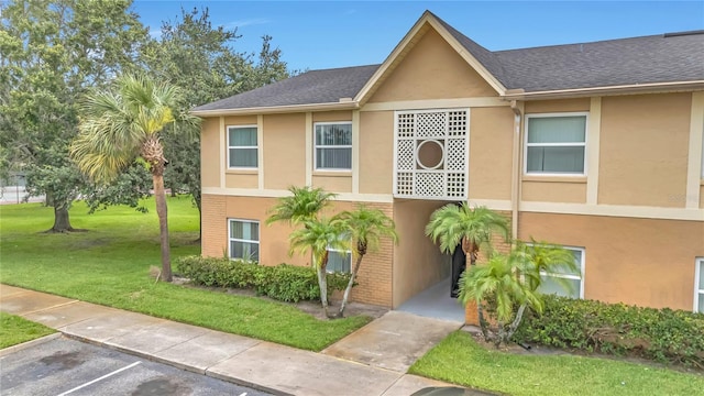 9900 Sweepstakes Ln Unit 1, Orlando, FL 32837 - view of front of house featuring a front yard, stucco siding, uncovered parking, and a shingled roof