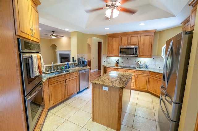 1550 Kevin Ln, Deland, FL 32724 - kitchen with appliances with stainless steel finishes, a ceiling fan, a kitchen island, arched walkways, and tasteful backsplash