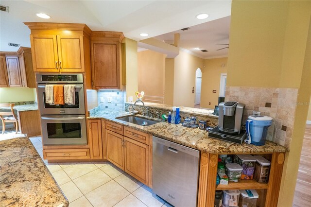 1550 Kevin Ln, Deland, FL 32724 - kitchen with appliances with stainless steel finishes, a sink, light stone countertops, crown molding, and a peninsula